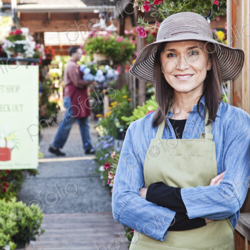 Caucasian woman owner of garden center nursery with a younger employee.