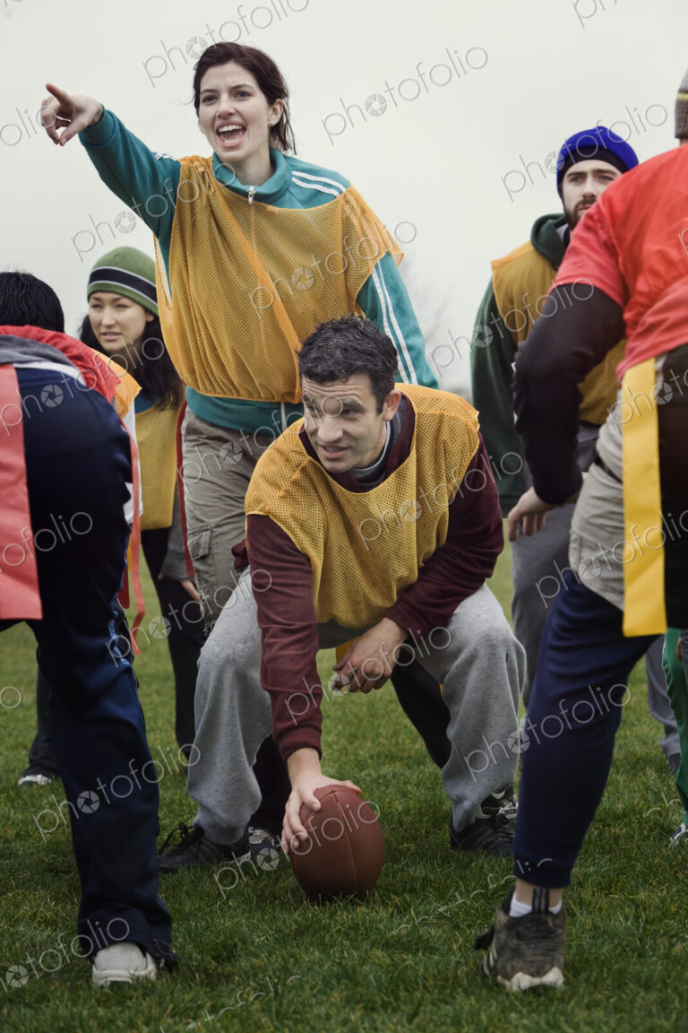 Caucasian woman playing quarterback for a team of friends playing non-contact flag…