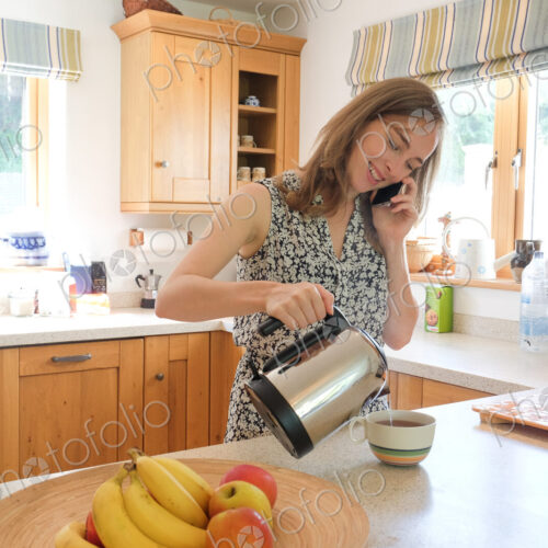 Caucasian woman poring coffee and talking on cell phone Caucasian woman poring coffee and talking on cell phone