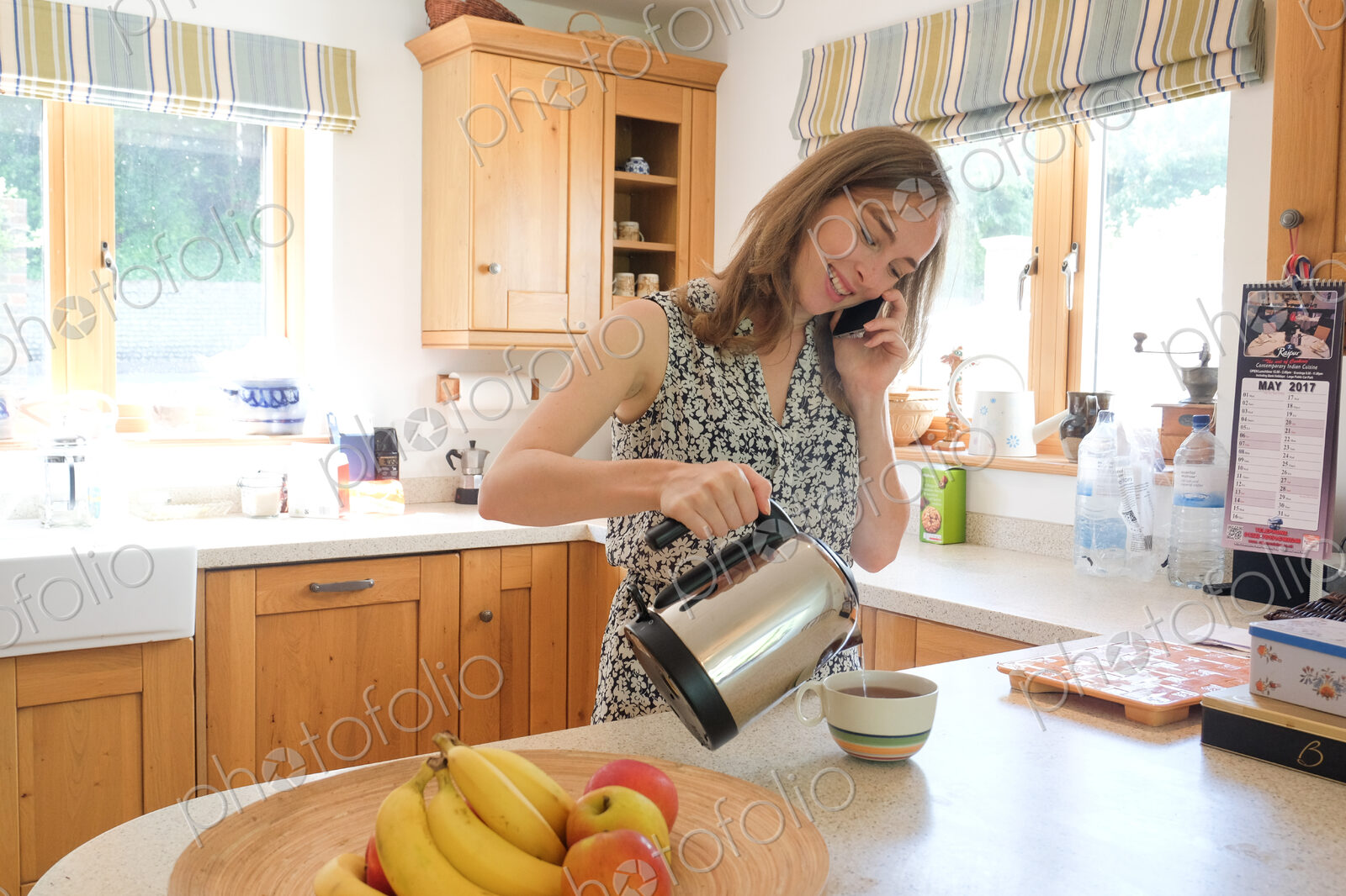 Caucasian woman poring coffee and talking on cell phone