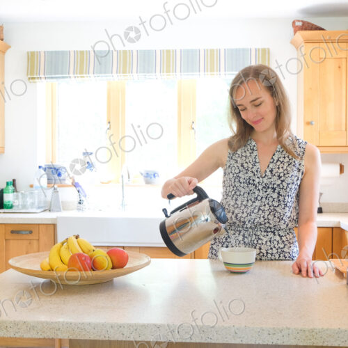 Caucasian woman poring coffee from pot in kitchen Caucasian woman poring coffee from pot in kitchen