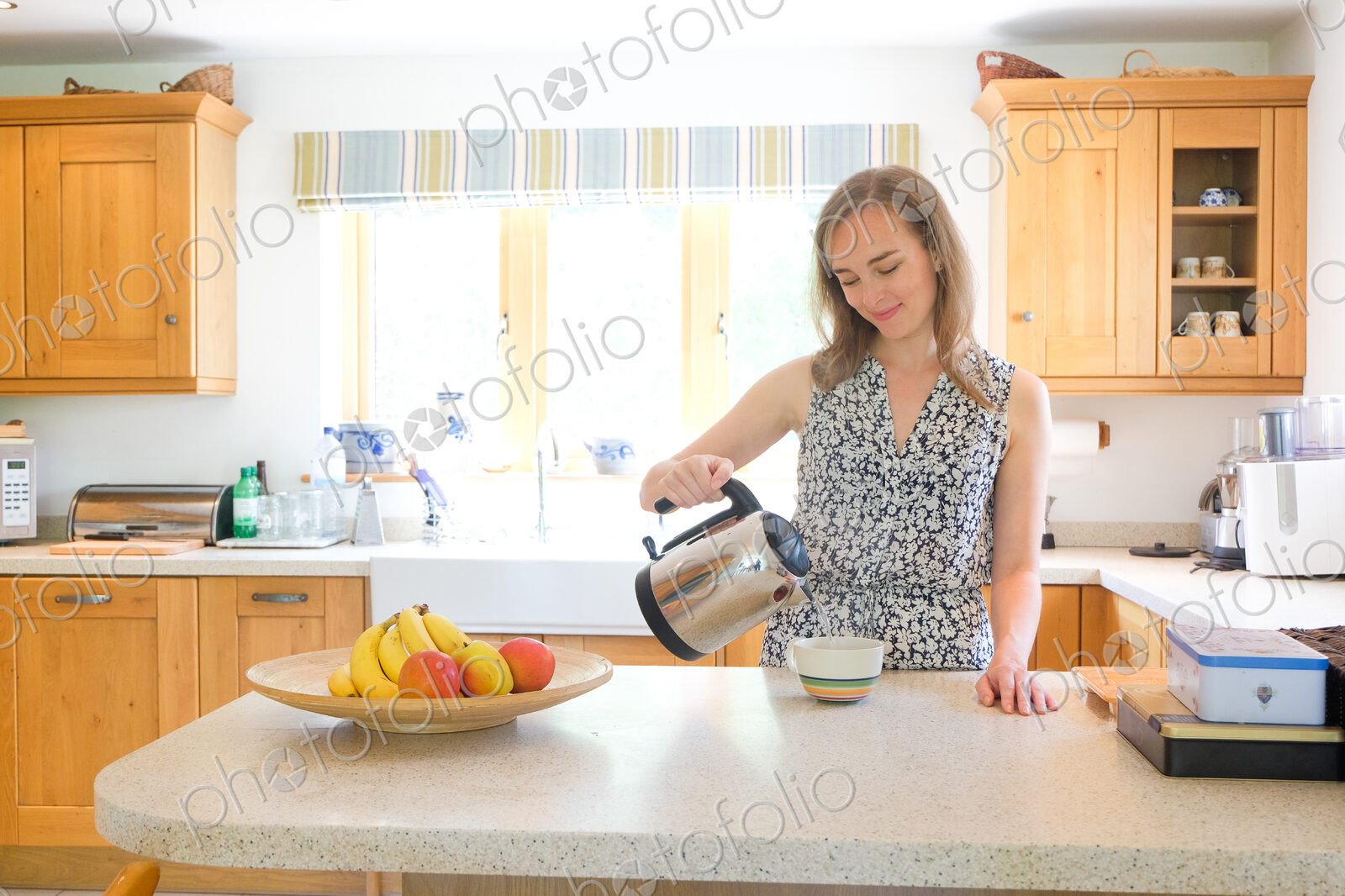 Caucasian woman poring coffee from pot in kitchen