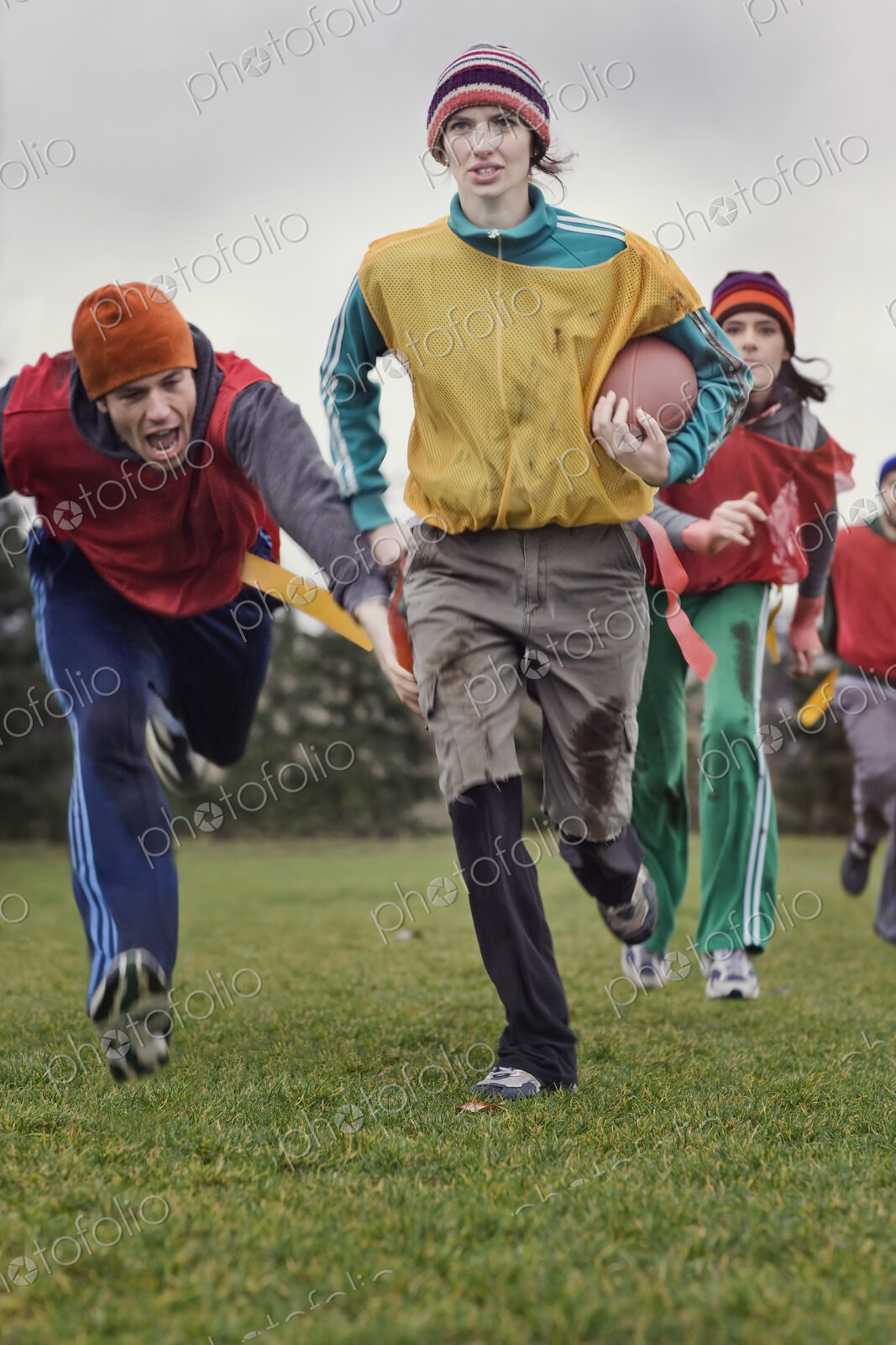 Caucasian woman running with the football in an non-contact flag football game.