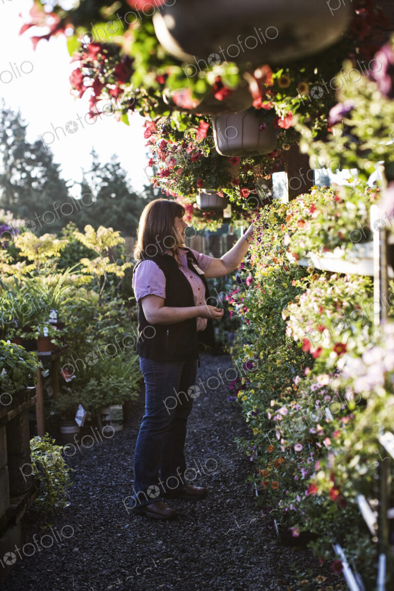 Caucasian woman shopping for new plants at a garden center nursery, choosing from a…