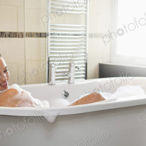 Caucasian woman taking bubble bath in bathroom