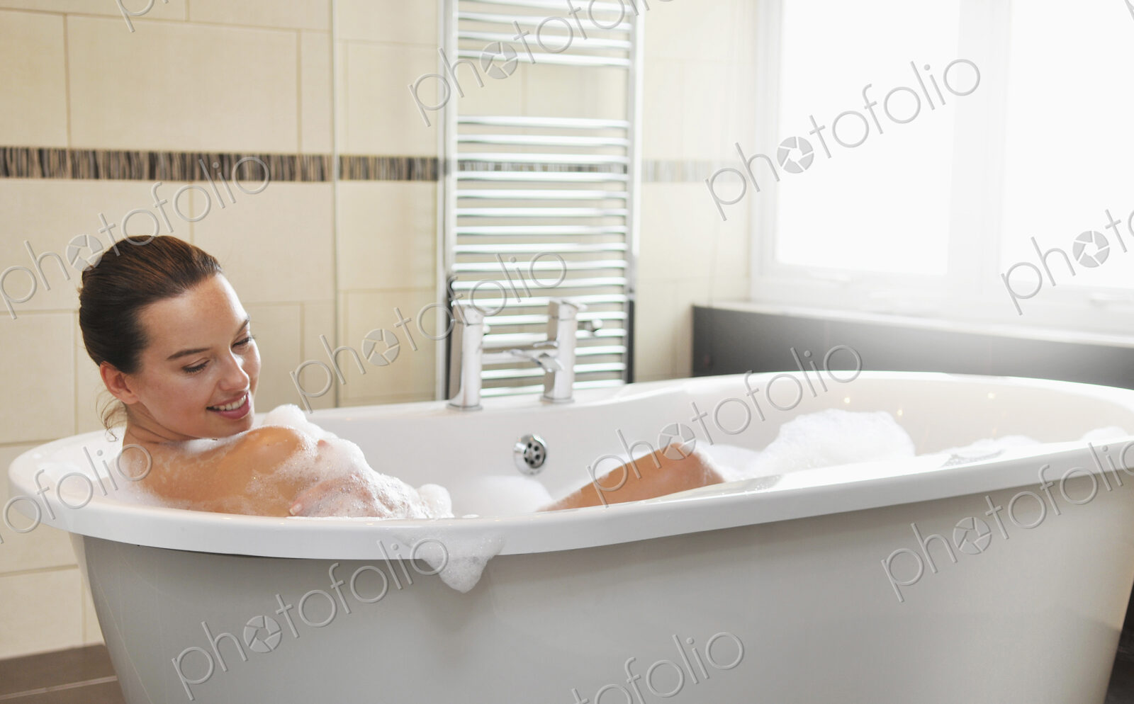 Caucasian woman taking bubble bath in bathroom