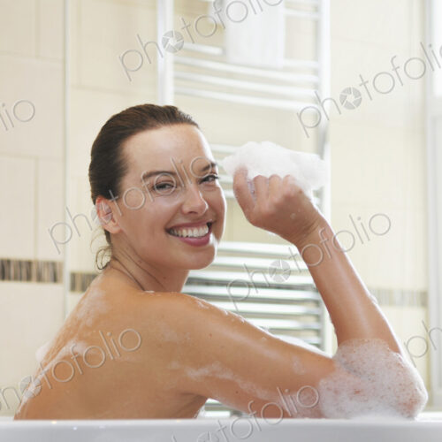 Caucasian woman taking bubble bath in bathroom