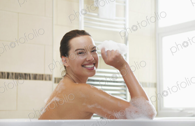 Caucasian woman taking bubble bath in bathroom