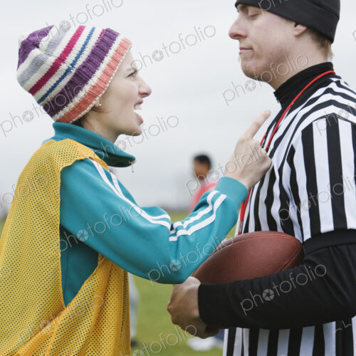 Caucasian woman team member arguig wtih a referee while playing non-contact flag football.