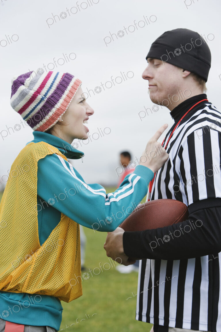 Caucasian woman team member arguig wtih a referee while playing non-contact flag football.