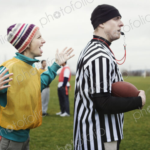 Caucasian woman team member arguig wtih a referee while playing non-contact flag football.