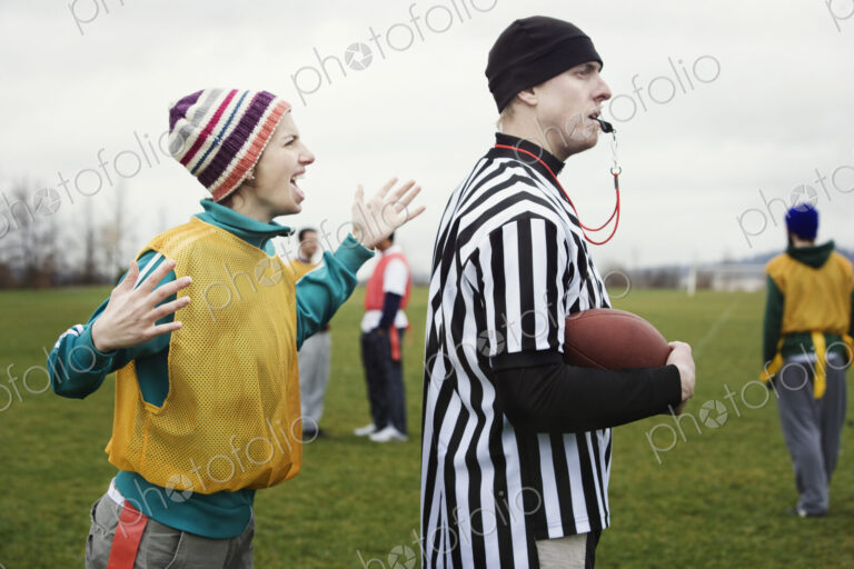 Caucasian woman team member arguig wtih a referee while playing non-contact flag football.