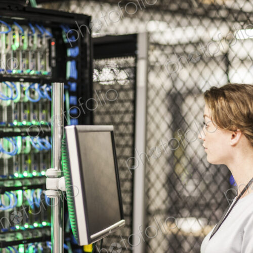 Caucasian woman technician doing diagnostic tests on computer servers in a server farm.