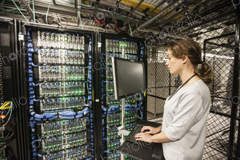 Caucasian woman technician doing diagnostic tests on computer servers in a server farm.