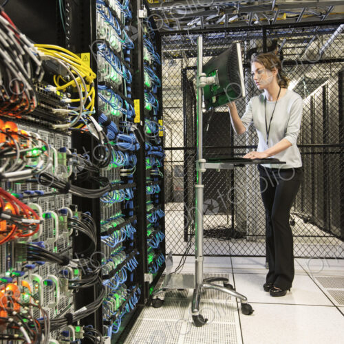 Caucasian woman technician doing diagnostic tests on computer servers in a server farm. Caucasian woman technician doing diagnostic tests on computer servers in a server farm.