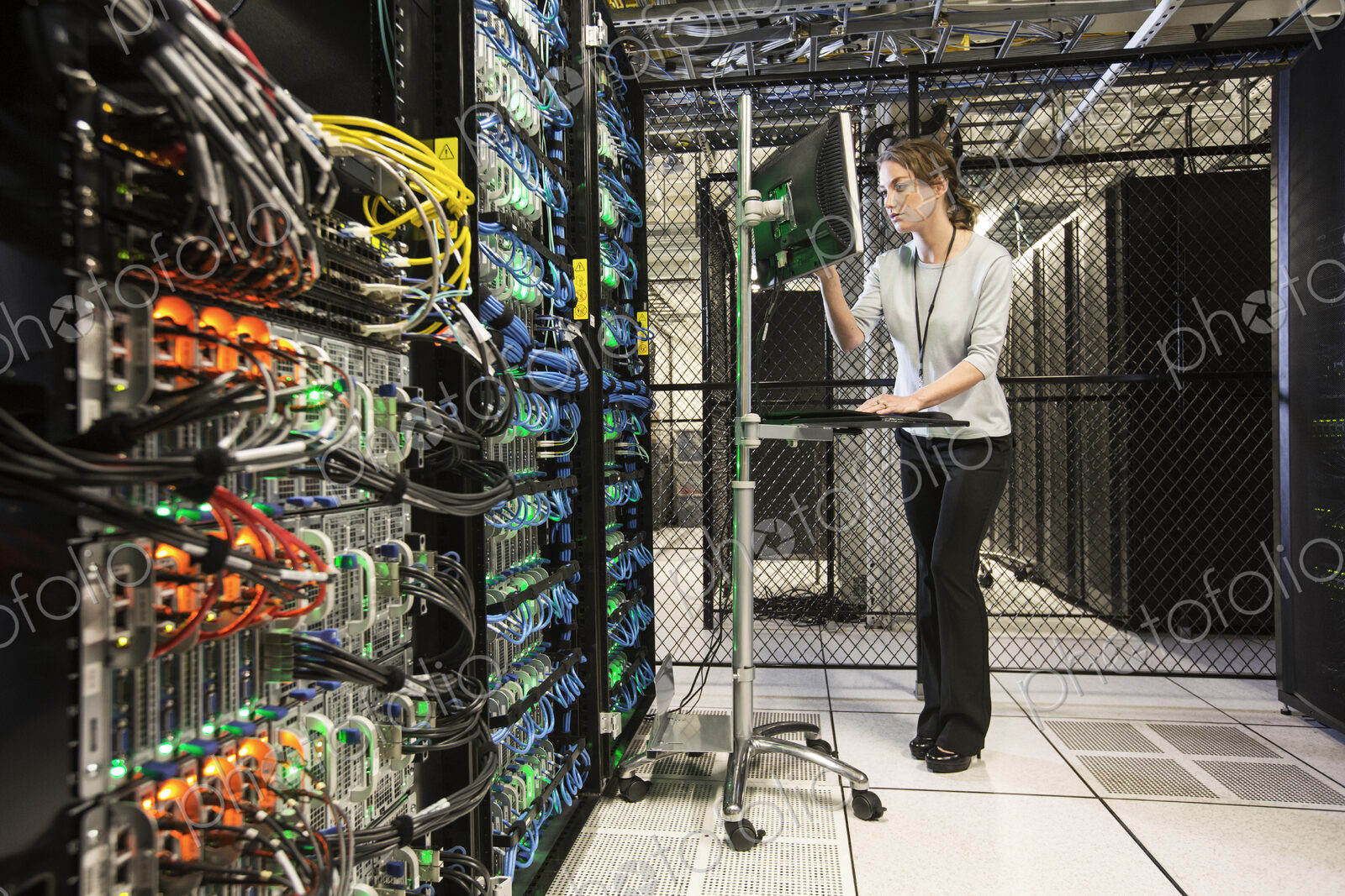 Caucasian woman technician doing diagnostic tests on computer servers in a server farm.