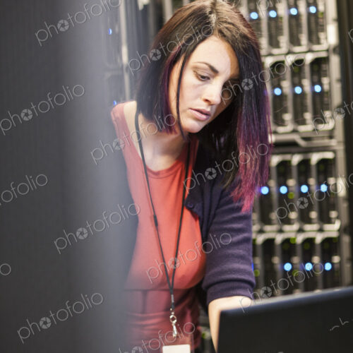 Caucasian woman technician in a large computer server farm.