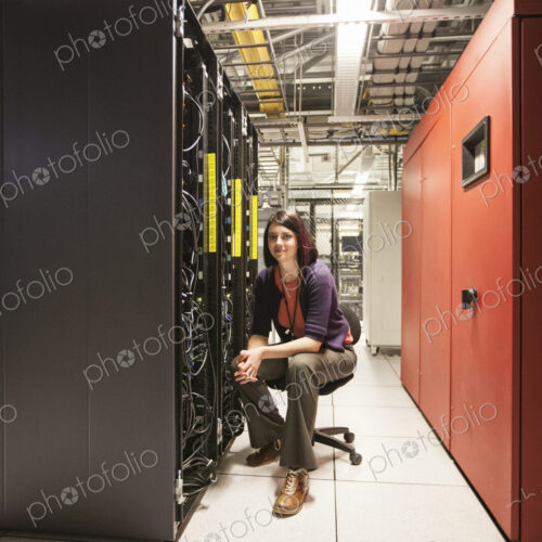 Caucasian woman technician in a large computer server farm.