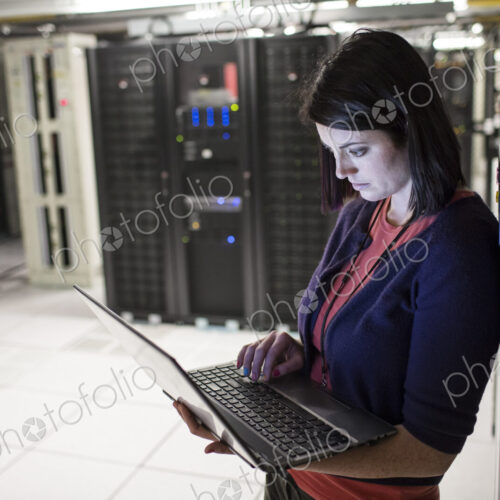 Caucasian woman technician in a large computer server farm. Caucasian woman technician in a large computer server farm.