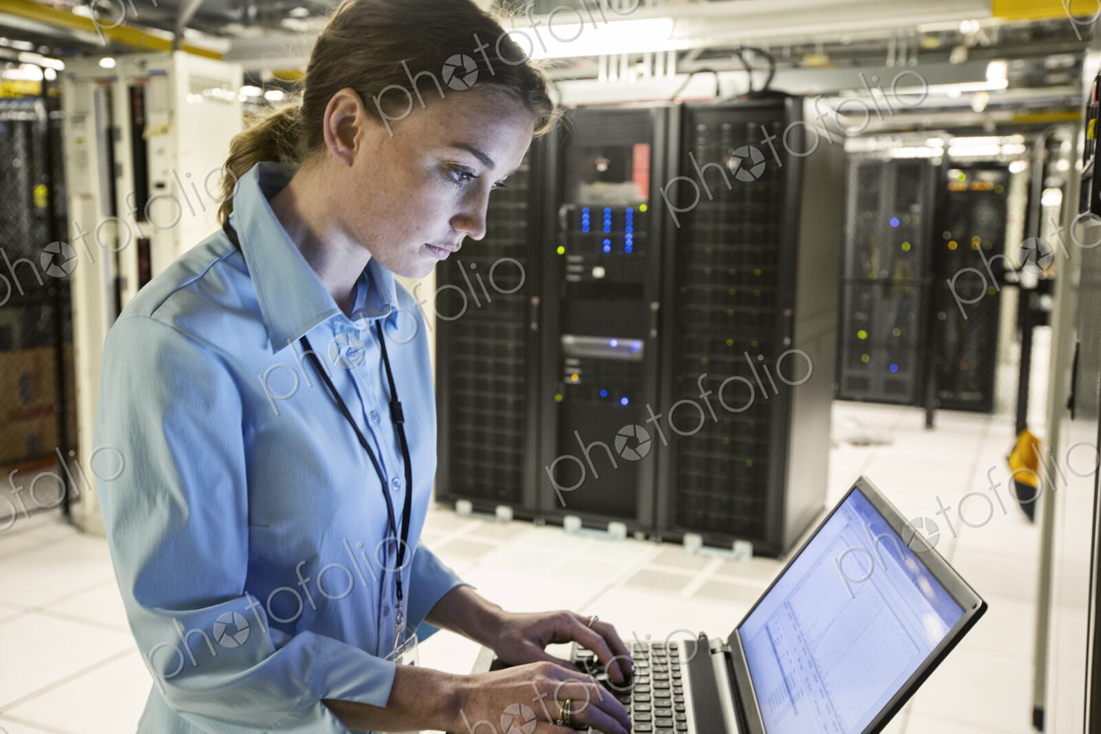 Caucasian woman technician running diagnostics on computer servers in a server farm.