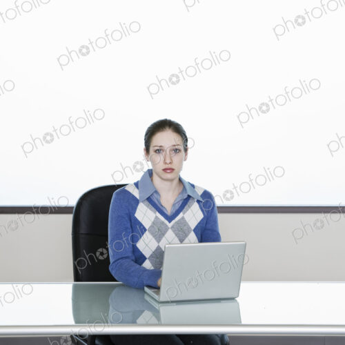 Caucasian woman technician working at lap top computer at a desk in a server farm office. Caucasian woman technician working at lap top computer at a desk in a server farm office.