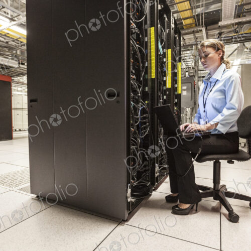 Caucasian woman technician working on computer servers in a server farm. Caucasian woman technician working on computer servers in a server farm.