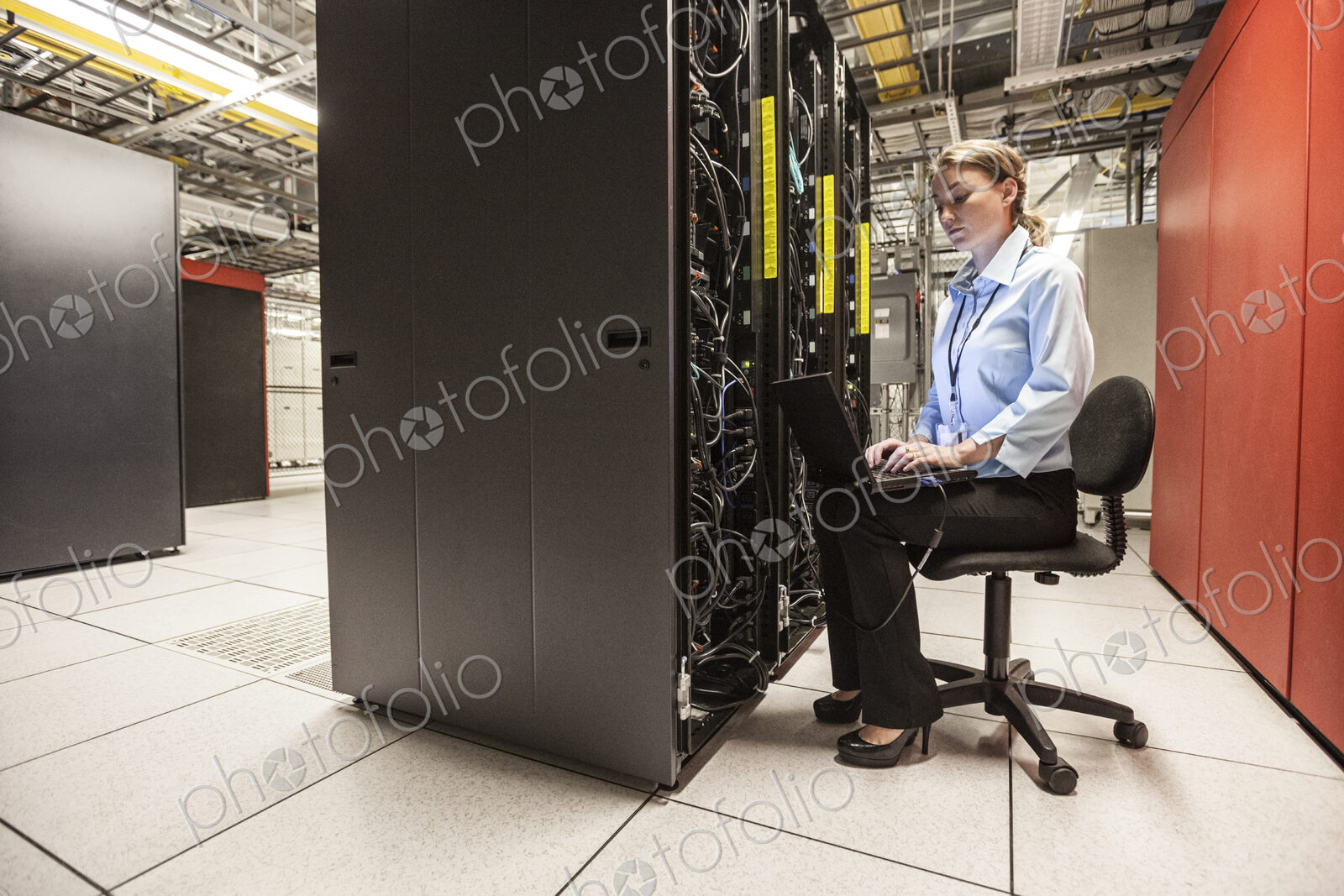 Caucasian woman technician working on computer servers in a server farm.