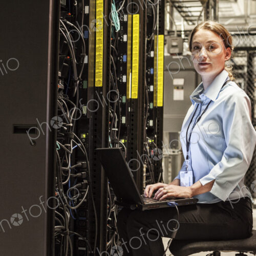 Caucasian woman technician working on computer servers in a server farm. Caucasian woman technician working on computer servers in a server farm.