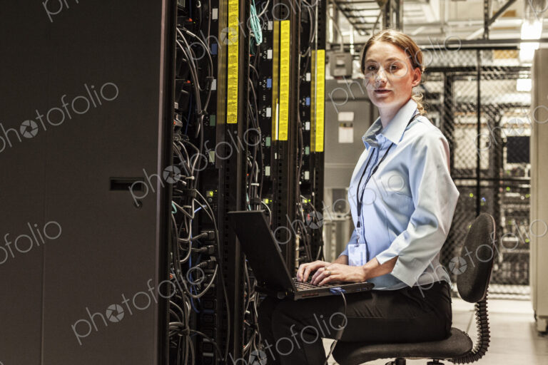 Caucasian woman technician working on computer servers in a server farm.