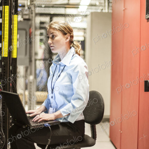 Caucasian woman technician working on computer servers in a server farm. Caucasian woman technician working on computer servers in a server farm.