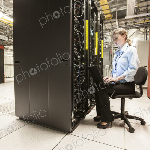 Caucasian woman technician working on computer servers in a server farm. Caucasian woman technician working on computer servers in a server farm.