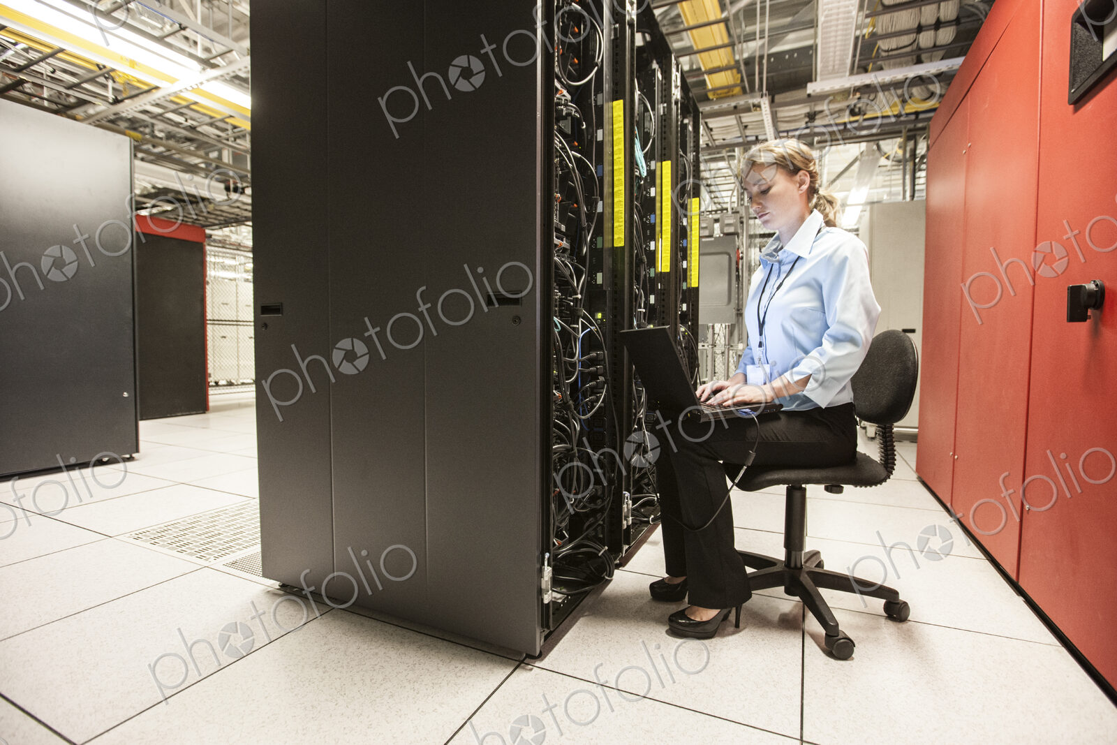 Caucasian woman technician working on computer servers in a server farm.