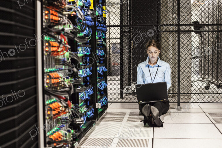 Caucasian woman technician working on computer servers in a server farm.