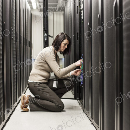 Caucasian woman technician working on computer servers in a server farm. Caucasian woman technician working on computer servers in a server farm.