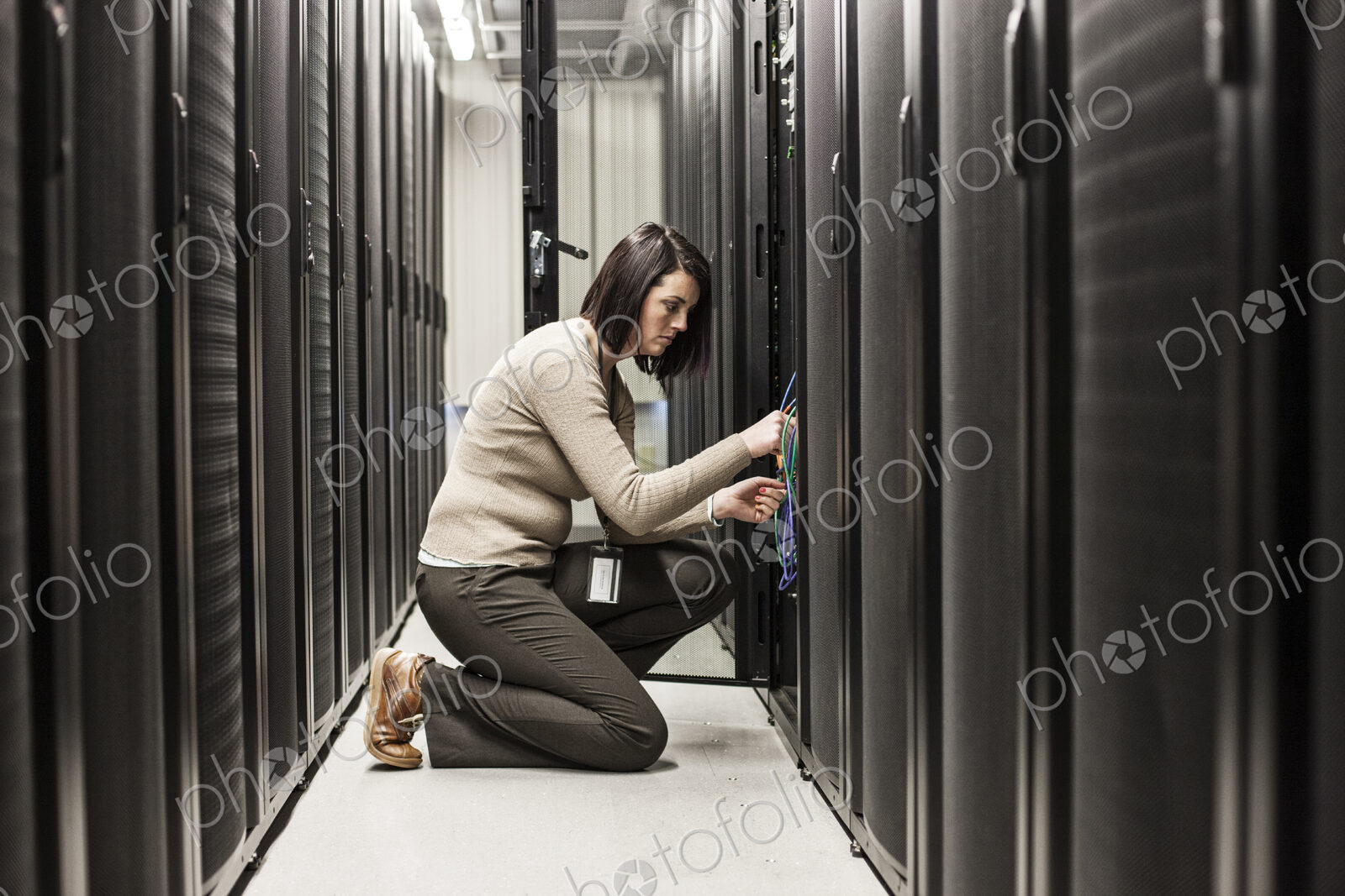 Caucasian woman technician working on computer servers in a server farm.