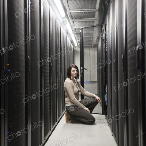 Caucasian woman technician working on computer servers in a server farm. Caucasian woman technician working on computer servers in a server farm.