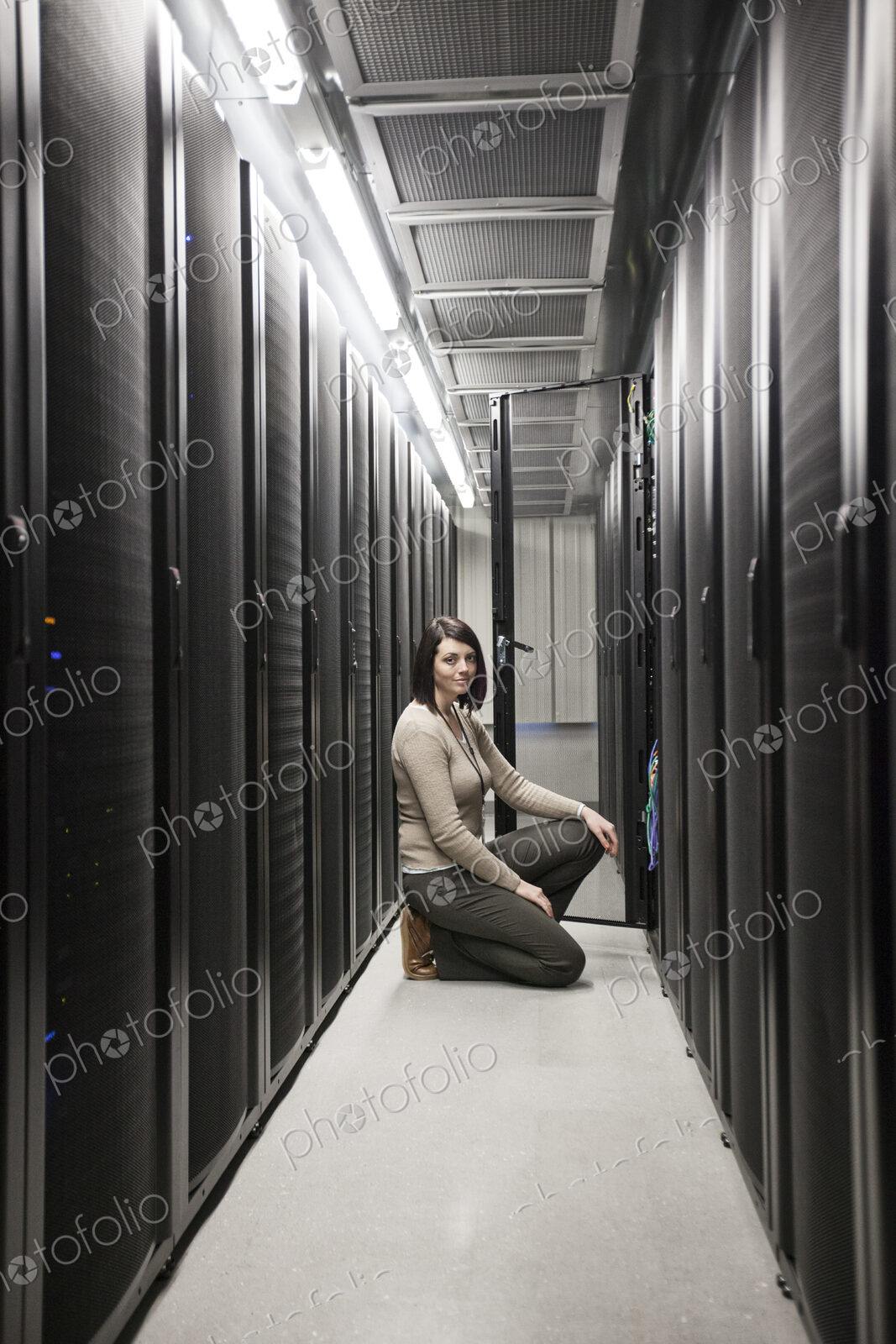 Caucasian woman technician working on computer servers in a server farm.