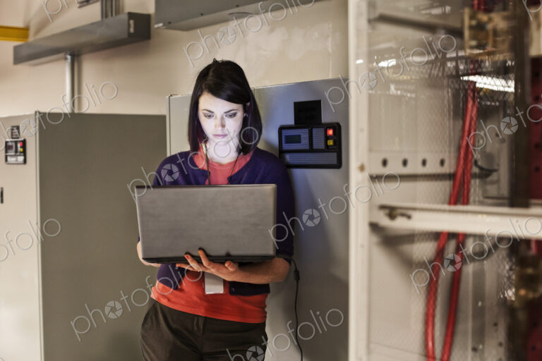 Caucasian woman technician working on computer servers in a server farm.