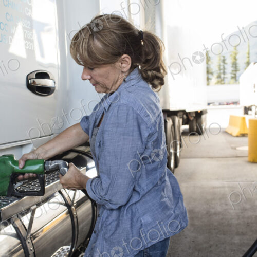 Caucasian woman truck driver filling truck with diesel fuel at a truck stop. Caucasian woman truck driver filling truck with diesel fuel at a truck stop.