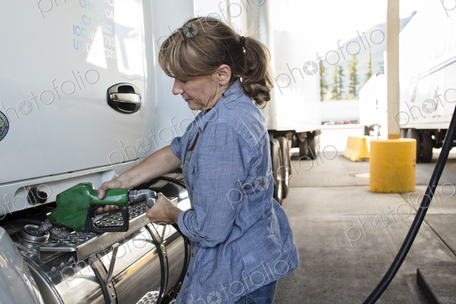 Caucasian woman truck driver filling truck with diesel fuel at a truck stop.
