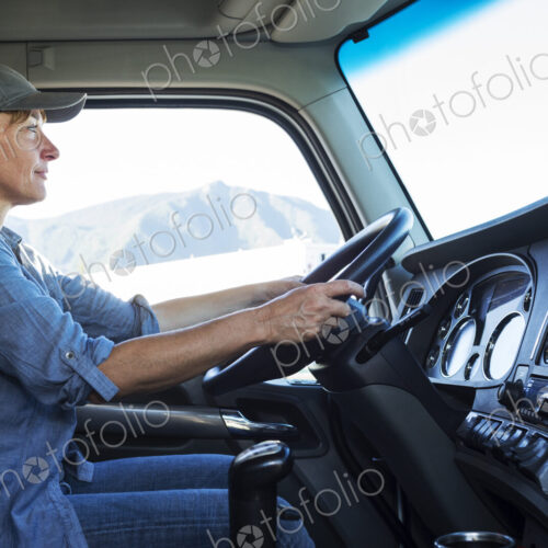 Caucasian woman truck driver in the cab of her commercial truck at a truck stop