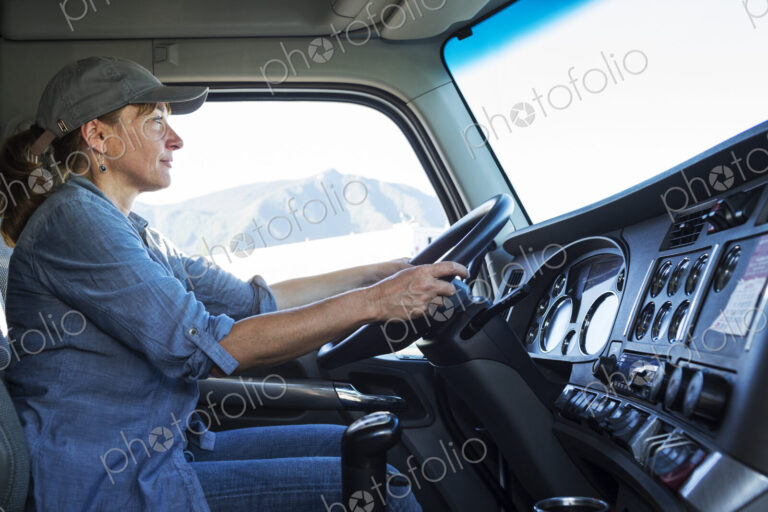Caucasian woman truck driver in the cab of her commercial truck at a truck stop