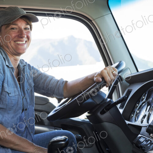 Caucasian woman truck driver in the cab of her commercial truck at a truck stop