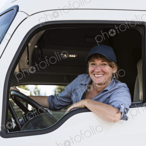 Caucasian woman truck driver in the cab of her commercial truck at a truck stop Caucasian woman truck driver in the cab of her commercial truck at a truck stop