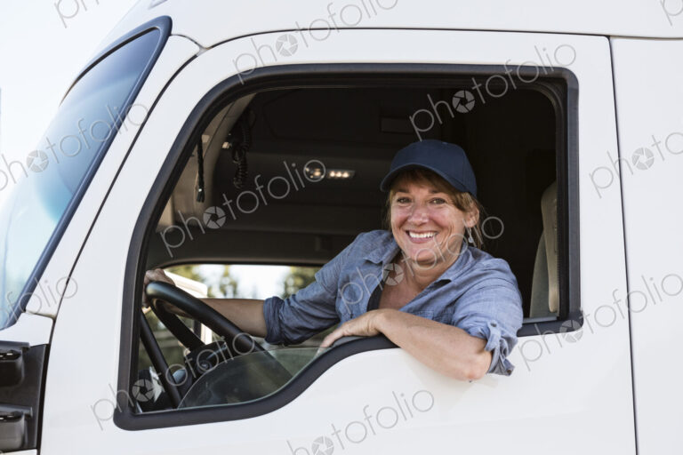 Caucasian woman truck driver in the cab of her commercial truck at a truck stop