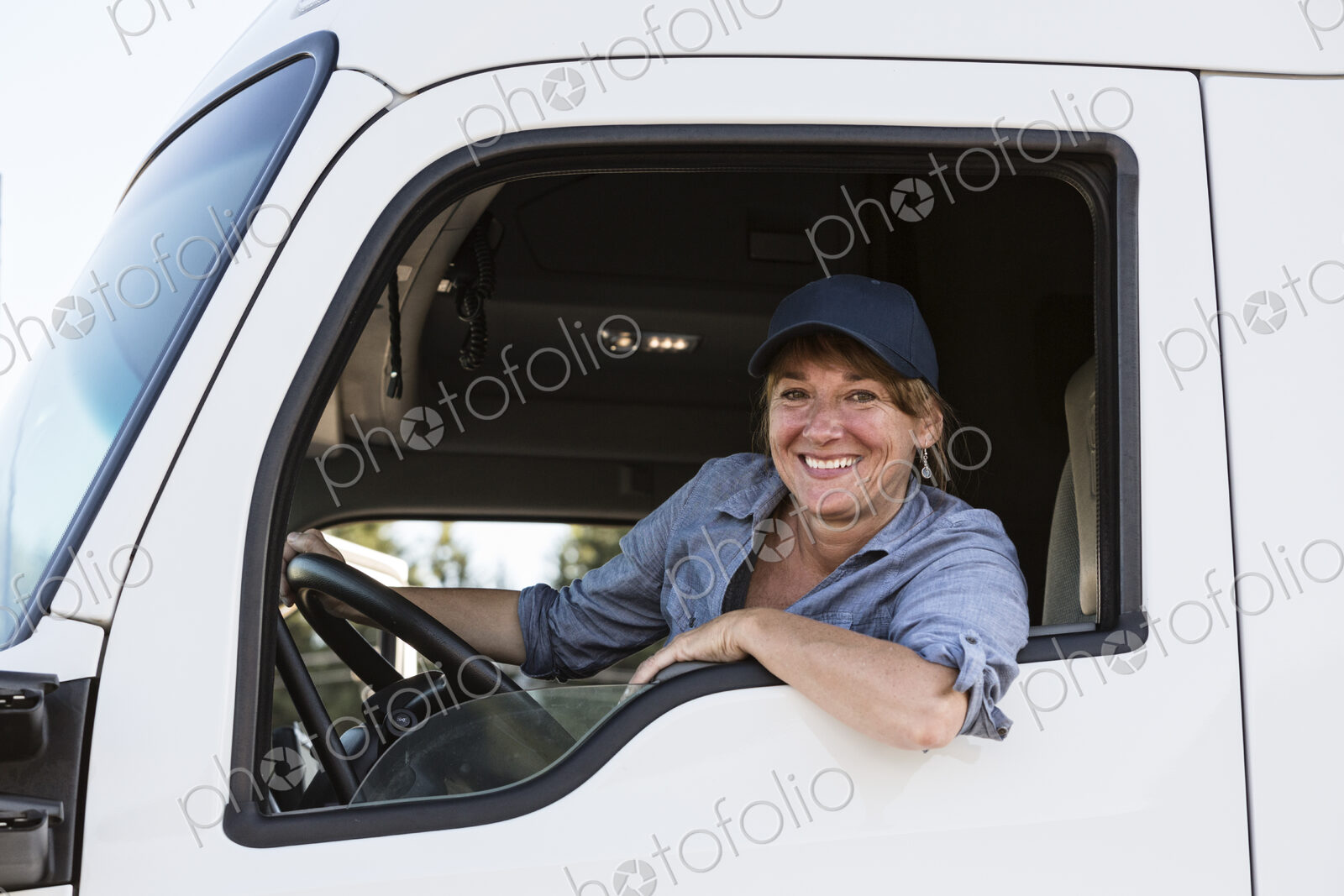 Caucasian woman truck driver in the cab of her commercial truck at a truck stop
