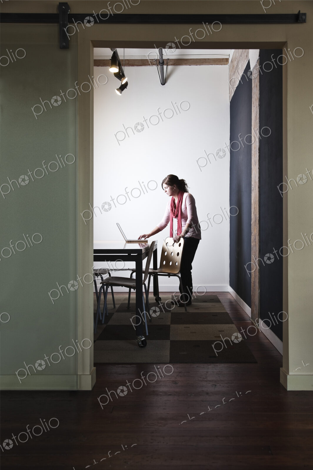 Caucasian woman working on a laptop computer in a small conference room.