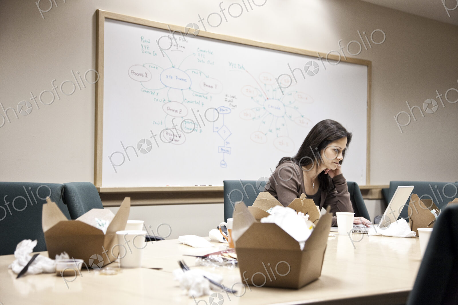 Caucasian woman working through lunch at a conference room table.