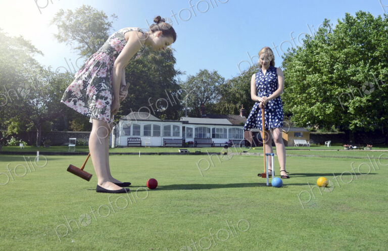 Caucasian women playing croquet on lawn