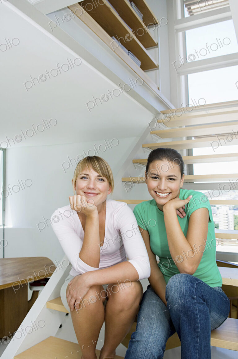 Caucasian women sitting on staircase in modern home